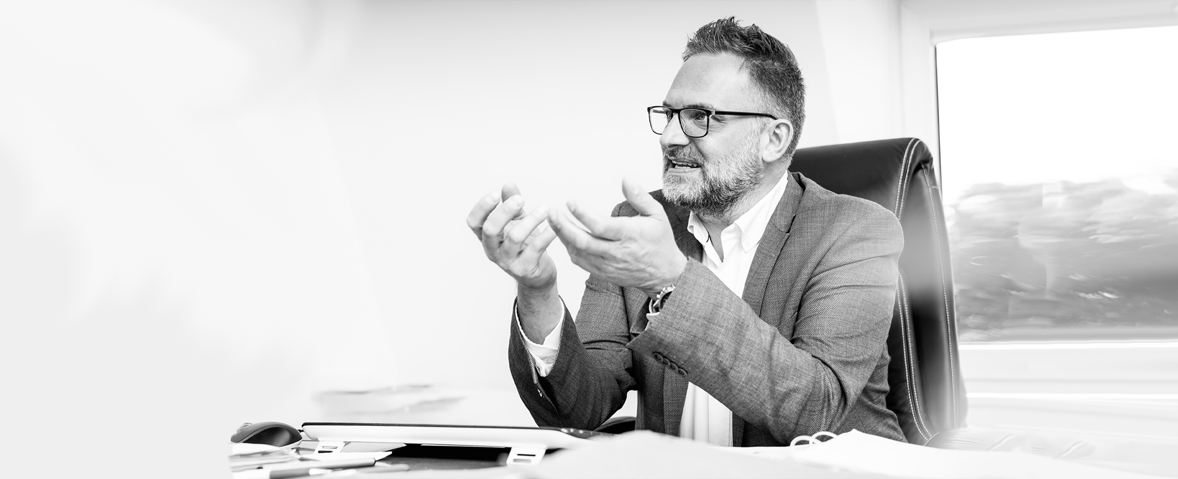Rechtsanwalt Klaus Kaczmaryk sitzt am Schreibtisch und erklärt etwas gestikulierend
