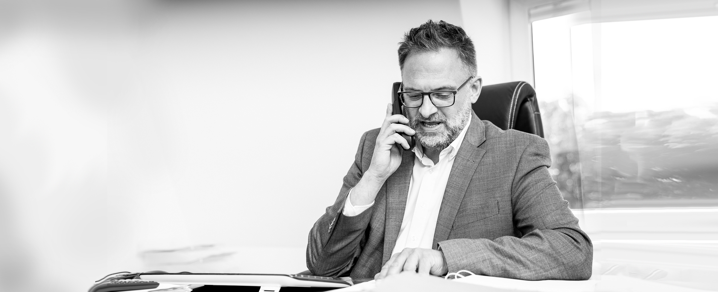 Rechtsanwalt Klaus Kaczmaryk sitzt am Schreibtisch und telefoniert. Er blickt dabei in seine Unterlagen
